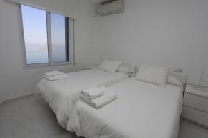 two beds in a white room with a window at Villas Romanas with best sunsets and views in Cartagena +39 photos
