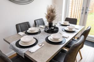 uma mesa de jantar com cadeiras pretas, pratos brancos e guardanapos em Spacious Luxury House In Canterbury with Free Parking EV, Sleeps 7 em Canterbury