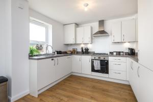 a white kitchen with white cabinets and a window at New Modern Luxury Cosy Home In Canterbury - Free Parking EV - Sleeps 7 in Sturry