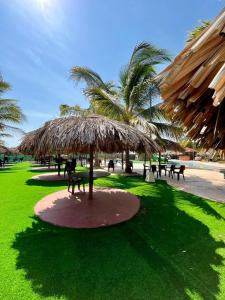 a large straw umbrella in a park with tables and chairs at Paradise Resort in Los Santos