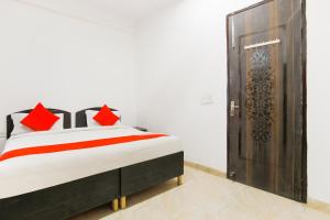 1 dormitorio con cama con almohadas rojas y puerta de madera en OYO Welcome Residency, en Gurgaon