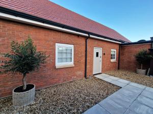 a brick building with a white door and a tree at Elevated Space Apartments, Shipston on Stour in Shipston on Stour