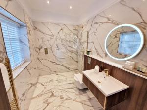bagno in marmo con lavandino e specchio di Elevated Space Apartments, Shipston on Stour a Shipston-on-Stour