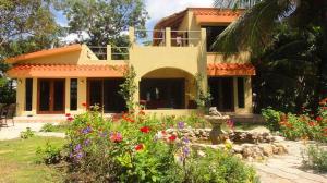 a house with a flower garden in front of it at Mermaid Manor Belize in White Hill