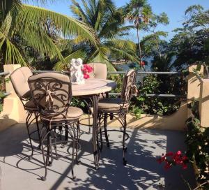 a table and chairs on a patio with palm trees at Mermaid Manor Belize in White Hill