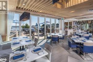 a restaurant with white tables and blue chairs and windows at Large Luxury Waterfront Penthouse in Collingwood