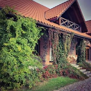 a house with ivy growing on the side of it at Poganty - Obora in Giżycko