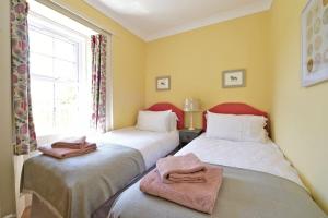 two beds in a room with a window at Fordel Cottage in Dalkeith