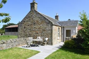 a stone house with a table and chairs in the yard at Fordel Cottage in Dalkeith