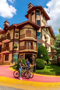 a man and woman riding bikes in front of a building at Pousada Villa D'Biagy in Campos do Jordão