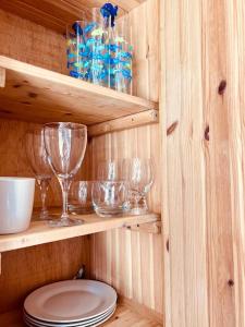 uma cabina de madeira com copos de vinho e pratos nas prateleiras em The Hideout em Linton