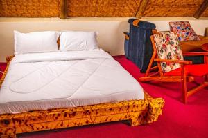 a bed and a chair in a room at Bugoma Sand Beach and Resort Hotel in Beta