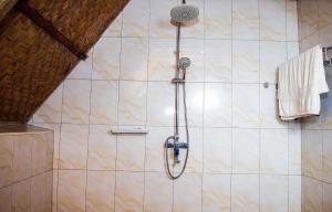 łazienka z prysznicem i ścianą wyłożoną kafelkami. w obiekcie Bugoma Sand Beach and Resort Hotel w mieście Beta