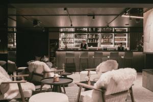 a restaurant with white chairs and a bar at TRIFORÊT alpinresort in Hinterstoder