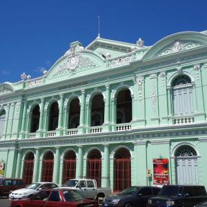 un edificio verde con macchine parcheggiate di fronte di Hoff Hostal y Restaurante a Santa Ana