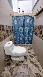 a toilet in a bathroom with a blue shower curtain at Casa Gaia: Un Paraiso in Mompiche