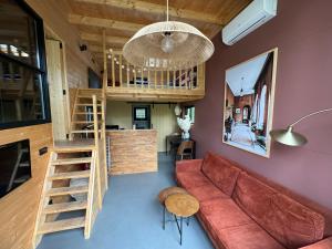 Tiny House Mayu - Veluwe Airco 4 persons في آرنم: غرفة معيشة مع أريكة حمراء ودور علوي