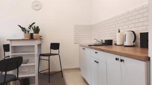 een keuken met witte kasten en een aanrecht met stoelen bij Studi-apartman Kestenov stan in Vršac