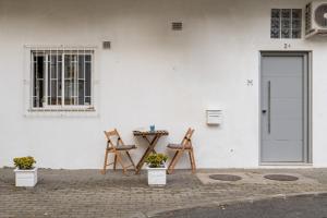 2 chaises et une table devant un mur blanc dans l'établissement Studio Nest - Near the train to Lisbon & Sintra, à Algueirão