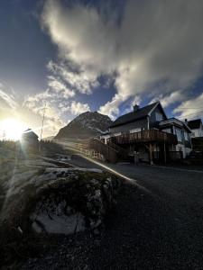 a house on the side of a road with the sun at KB Basement Apartment in Sørvågen