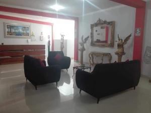 a living room with two chairs and a table and a mirror at Hostal Los Angeles in Tarapoto