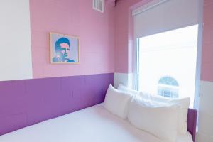 Habitación rosa con cama y ventana en The Gallatin, en Nashville