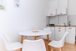 małą kuchnię ze stołem i białymi krzesłami w obiekcie Apartmani Zvirac w mieście Sokobanja