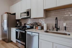 a kitchen with white cabinets and stainless steel appliances at Chic Studio Walk to SMM SLU Hospital Grand in Tower Grove
