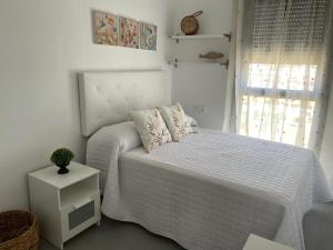a white bedroom with a bed and a window at piso recinto ferial en teatinos in Málaga