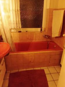 uma banheira vermelha na casa de banho com uma janela em Pro Viva em Oberhausen