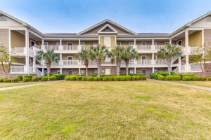an exterior view of a large apartment building with a yard at North Myrtle Beach Condo Rental with Pool Access! in North Myrtle Beach