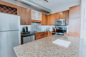 a kitchen with wooden cabinets and a white refrigerator at Luxe 2BR-1BA Penthouse w Balcony & Pool in Tower Grove