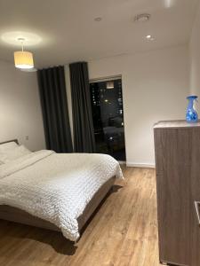 Schlafzimmer mit einem weißen Bett und Holzboden in der Unterkunft Simply lux apartment in London