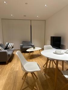 ein Wohnzimmer mit einem Sofa, einem Tisch und Stühlen in der Unterkunft Simply lux apartment in London