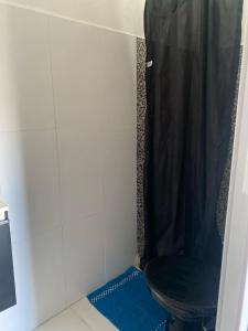 a bathroom with a toilet with a black shower curtain at Kit net linda e aconchegante in Cabo Frio