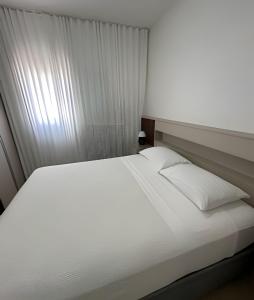 a white bed in a room with a window at Casa Bela Vista no centro São Roque in São Roque