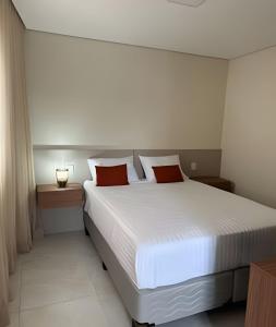 a bedroom with a large white bed with red pillows at Casa Bela Vista no centro São Roque in São Roque