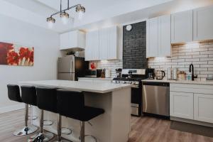a kitchen with white cabinets and a large island with bar stools at Luxe 2BR Oasis Patio & Laundry Soulard in Soulard