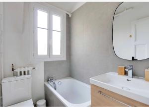 a bathroom with a tub and a sink and a mirror at Appartement, cœur des Batignolles Montmartre in Paris +4 photos