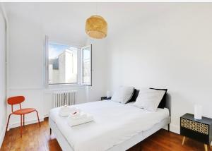 a white bedroom with a white bed and a chair at Appartement, cœur des Batignolles Montmartre in Paris