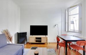 a living room with a flat screen tv on a white wall at Appartement, cœur des Batignolles Montmartre in Paris