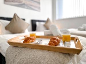 a tray with two croissants and two glasses of orange juice at Contemporary and Cosy Birmingham Apartment- Free Parking & Wi-FI in Birmingham