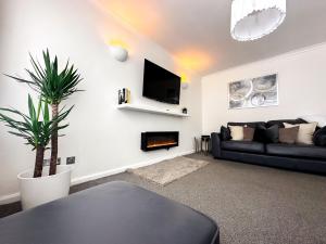 una sala de estar con un sofá negro y una planta en Contemporary and Cosy Birmingham Apartment- Free Parking & Wi-FI en Birmingham
