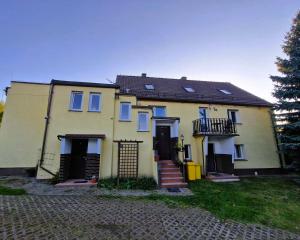 a yellow house with a black roof and a yard at Rozbrykany Muflon in Witoszów Dolny