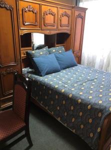 - un lit avec une tête de lit en bois et des oreillers bleus dans l'établissement Private room near Metro 5 Bobigny, à Bobigny