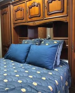 - un lit bleu avec une tête de lit en bois et des oreillers bleus dans l'établissement Private room near Metro 5 Bobigny, à Bobigny