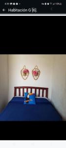 um quarto com uma cama azul com duas flores na parede em Sancarlosbeach em San Carlos