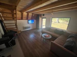 ein Wohnzimmer mit einem Sofa, einem TV und einer Treppe in der Unterkunft Eden in Žabljak