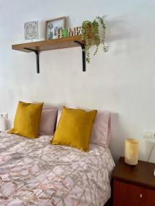 1 dormitorio con cama con almohadas amarillas y estante en La Casita de las Hermanas, en Málaga