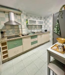 cocina con paredes de azulejos verdes y blancos en La Casita de las Hermanas, en Málaga